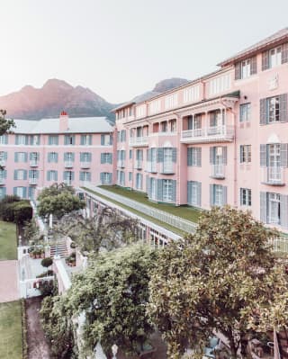 Glamorous colonial style hotel with pink facade beside Table Mountain