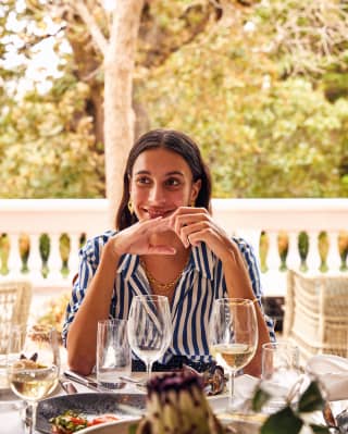 A smiling woman in a striped shirt sat at the dining table
