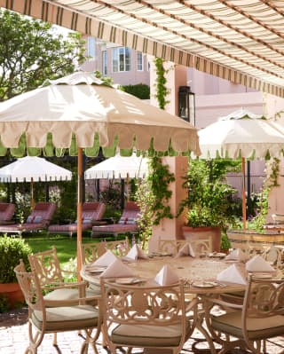 A laid table with eight chairs awaits guests on Oasis Bistro's terrace, where a canopy and parasols create abundant shade.