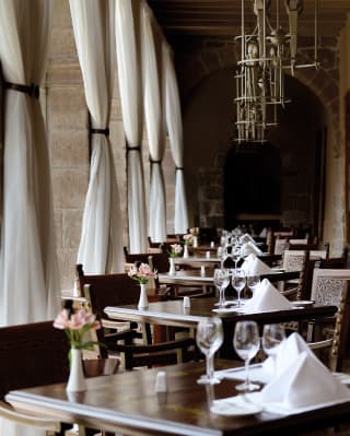 Square tables lining an arched cloister with modern hanging chandeliers