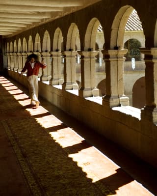 A smiling woman walking gleefully in the corridors of the Monasterio