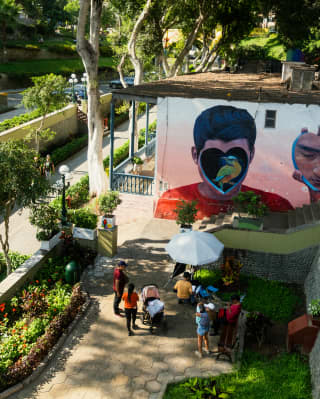 People gather to look at a mural of a bird inside a heart covering a boy's face, seen from above in the district of Barranco.