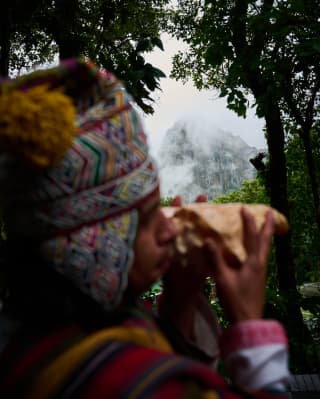 A shaman in a traditional chullo cap blows incense smoke into the air as an offering to mother earth at a Pachamama ceremony.