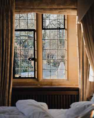 Wine glasses on a table through an ivy surrounded window