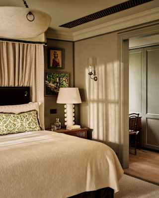 Peak through white curtains to a perfectly made bed beyond