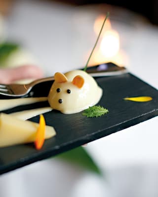 Close-up of a cheese-mousse in the shape of a mouse on a black slate 