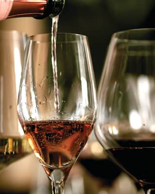 Close-up of rosé wine being poured into a wine glass