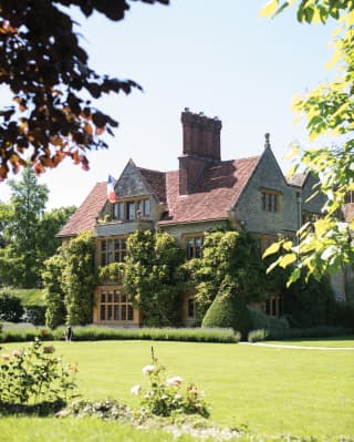 The ivy clad manor house stands amid manicured lawns and lavender borders. A single French Tricolour hangs from a flagpole