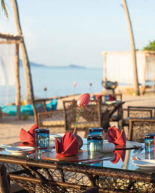 Wicker and bamboo restaurant table on a beach with red and blue accents