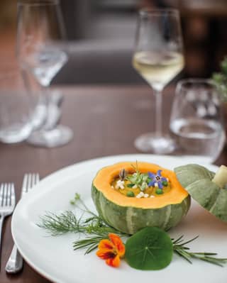 Close-up of white circular plate with pumpkin dish garnished with flowers