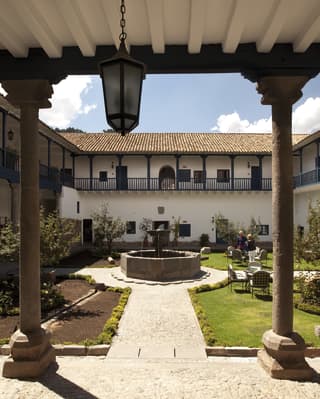 The hotel’s period courtyard garden with tables and chairs around a stone fountain at the centre