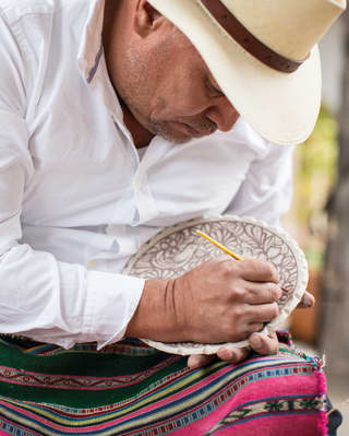 Close-up of artist Tater Vera hand painting a ceramic bowl