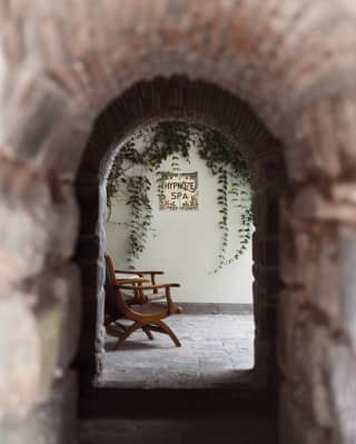 View through an arched stone doorway of two chairs under a sign for Hypnôze Spa