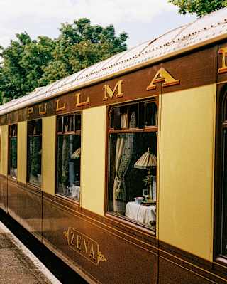 External side-on view of a cream and maroon train carriage with name Zena below the windows and Pullman painted above.