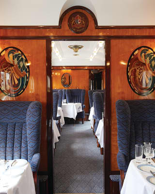 View through the aisle of a vintage train carriage with navy blue armchair seating