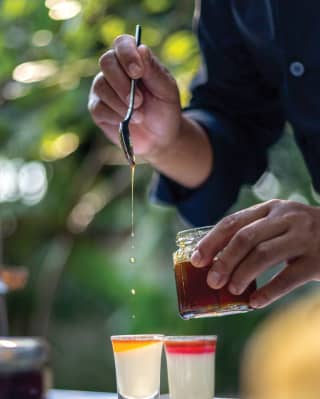 Close-up of honey being drizzled into two glasses of fresh juice