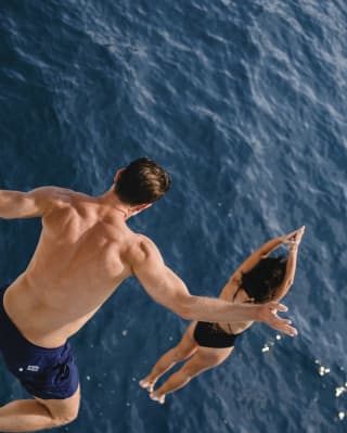 Couple leaping into a deep blue ocean