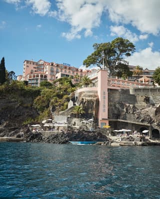 Pink facade of a Victorian hotel spread across a cliffside overlooking the sea