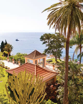 View from the hillside gardens across green terraces and terracotta-tiled pagodas, over poolside lawns and out to sea.