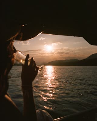 A female guest enjoys a cruise on the Mekong River, sipping champagne and gazing out at the silky waters and setting sun.