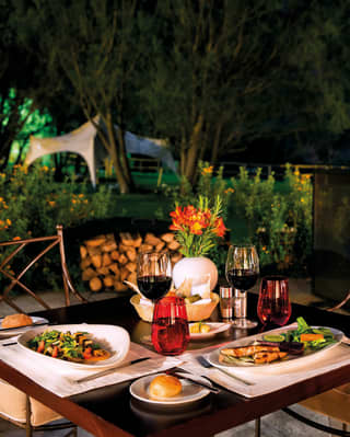 Restaurant terrace at night with a table laden with contemporary Peruvian cuisine