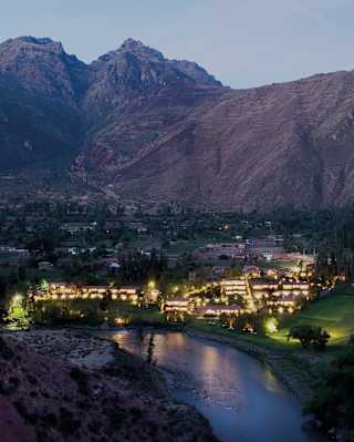 The Urubamba River reflects of the lights of Rio Sagrado, which glows in a high-angle late evening view of the Sacred Valley.