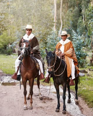 Close-up of two horseback riders in traditional gaucho dress