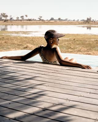 Lady leaning back on the side of a safari outdoor swimming pool