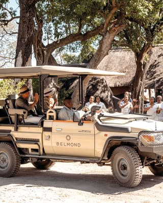 Two smiling guests arriving at a safari lodge in an overland safari vehicle
