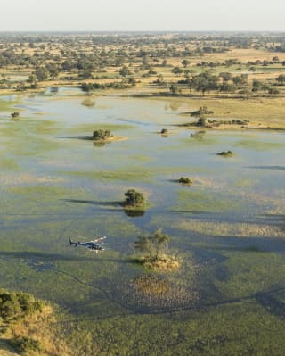A helicopter skims low over the water of the Okavango Delta Near Eagle Island Lodge