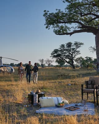 Guests walking away from a helicopter towards a picnic laid out on a blanket