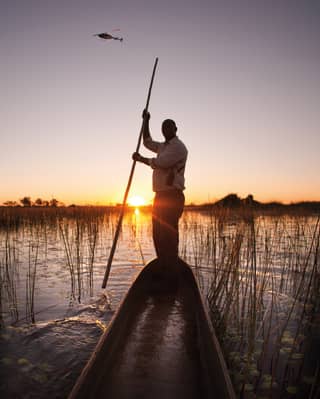 Guests enjoy a sunset canoe expedition in the Botswana wetlands