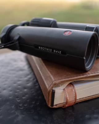 Leica binoculars set atop a journal