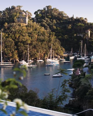 The dark blue pool echoes the colour of the Bay below, where a flotilla of sailing boats are moored close to tree-lined cliffs