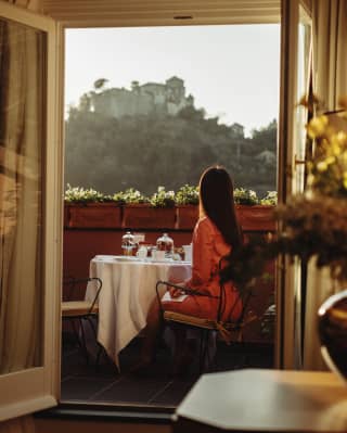 A woman sitting at a breakfast table on a balcony