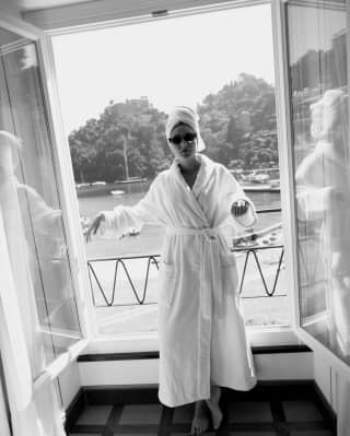 Black and white image of lady in bathrobe and sunglasses on a balcony