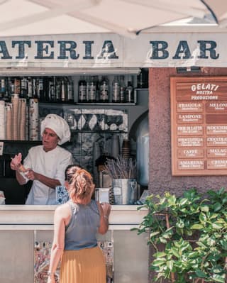 A lady requesting an ice cream from a vendor at an outdoor gelateria stand