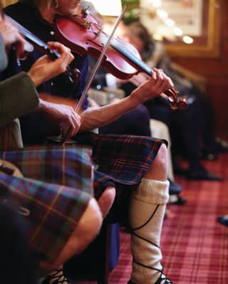Close-up of musicians wearing kilts and playing violins