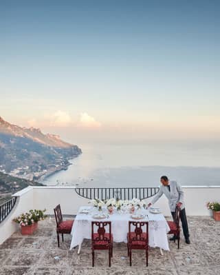A waiter set up a party table on the balcony over looking Amalfi coast
