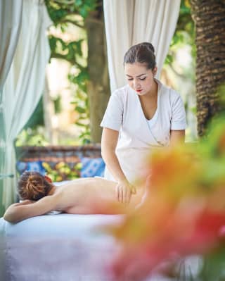 Spa therapist massaging a guest in an open air spa gazebo