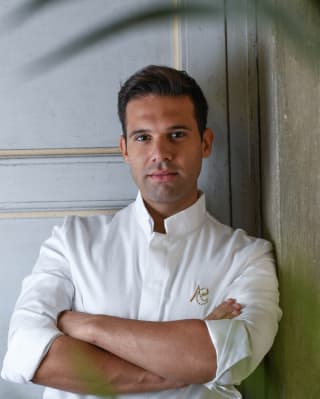 Chef Alessandro Cozzolino in chef whites standing cross-armed with a confident expression
