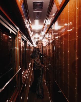 Mulher em vestido de gala olhando para um vagão de trem