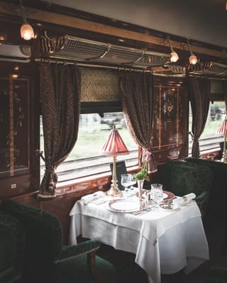 Vintage train dining car with French-polished wood panels and green velvet chairs