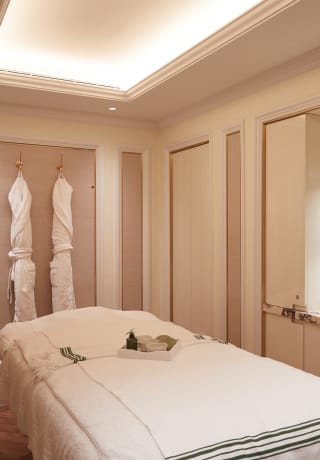 Spa treatment room with dusky pink panelled walls and hanging bathrobes