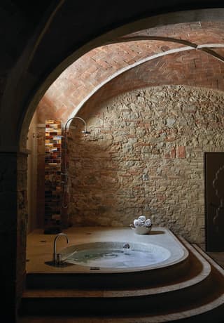 Circular hot tub in a rustic, underground, stone-walled spa>