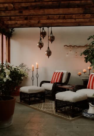 Two wicker chairs with foot stools await guests at the spa, serene with natural décor, candles, pendant lights and plants.>