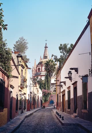 Curved cobblestone street lined with pastel coloured colonial-style homes