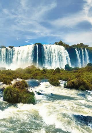 The Iguassu waterfalls crashing over the edge of a plateau