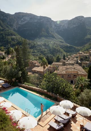 Lady standing at the edge of an outdoor pool surrounded by lush gardens