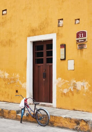 Una puerta y una pared color amarillo brillante de una casa en Izamal